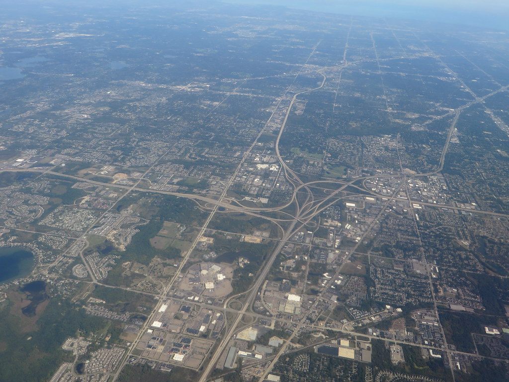 Aerial view of the I-96, I-696 and M-5 freeway interchange in Novi, with warehouses and subdivisions around it