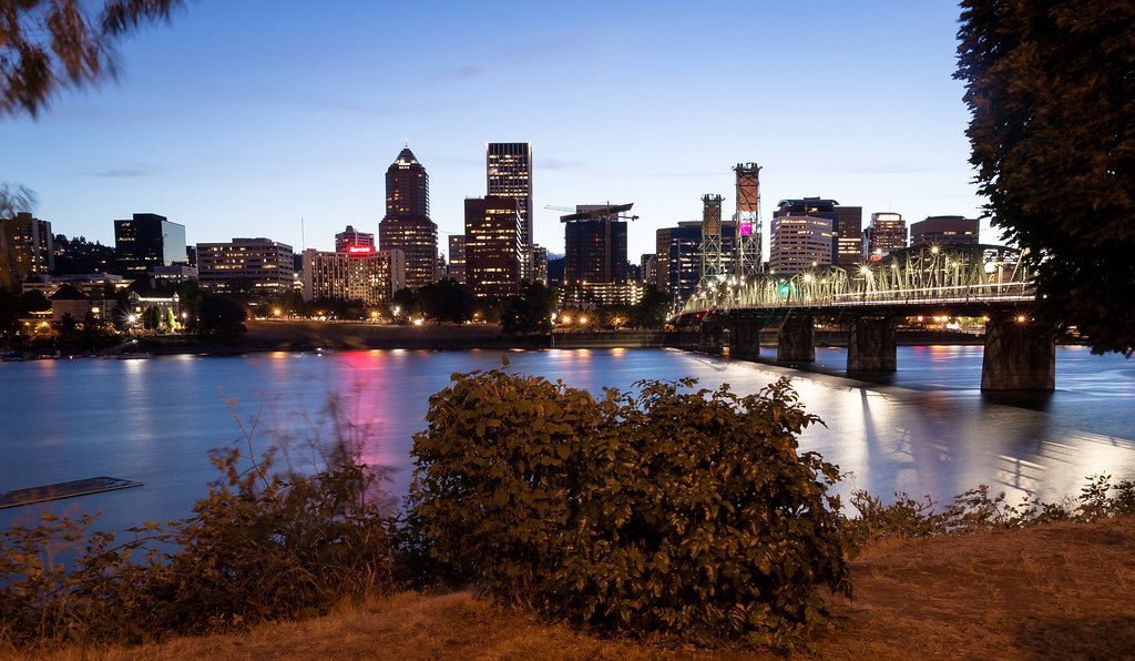Downtown Portland's lit towers and the Hawthorne Bridge reflected in the Willamette River at dusk