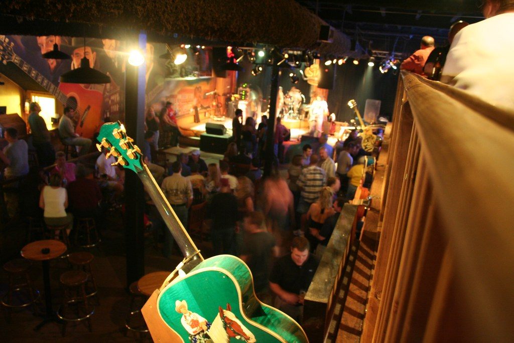 A packed Nashville bar watches a live band from the floor and the balcony rail