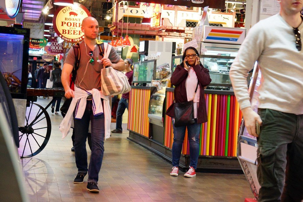 Shoppers walking past colorful food counters inside Reading Terminal Market in Philadelphia