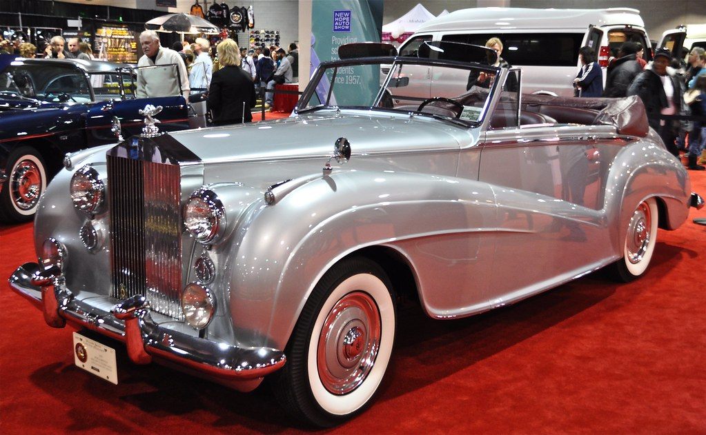 A silver vintage Rolls-Royce drophead on red carpet with show-goers milling behind it at the 2011 Philadelphia Auto Show