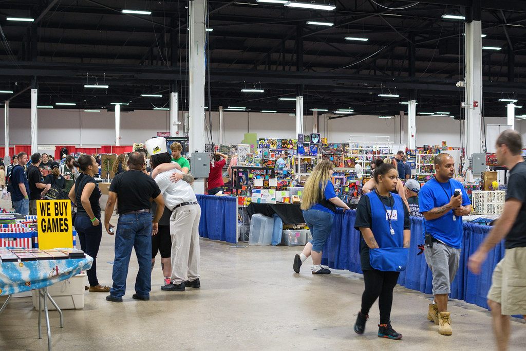 Shoppers and blue-vested staff moving through vendor aisles under the open steel trusses of the Greater Philadelphia Expo Center during Retro Con