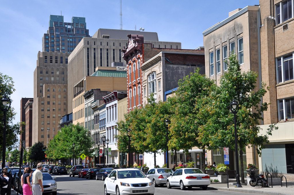 Downtown Raleigh street with Victorian storefronts, street trees and office towers behind on a sunny day