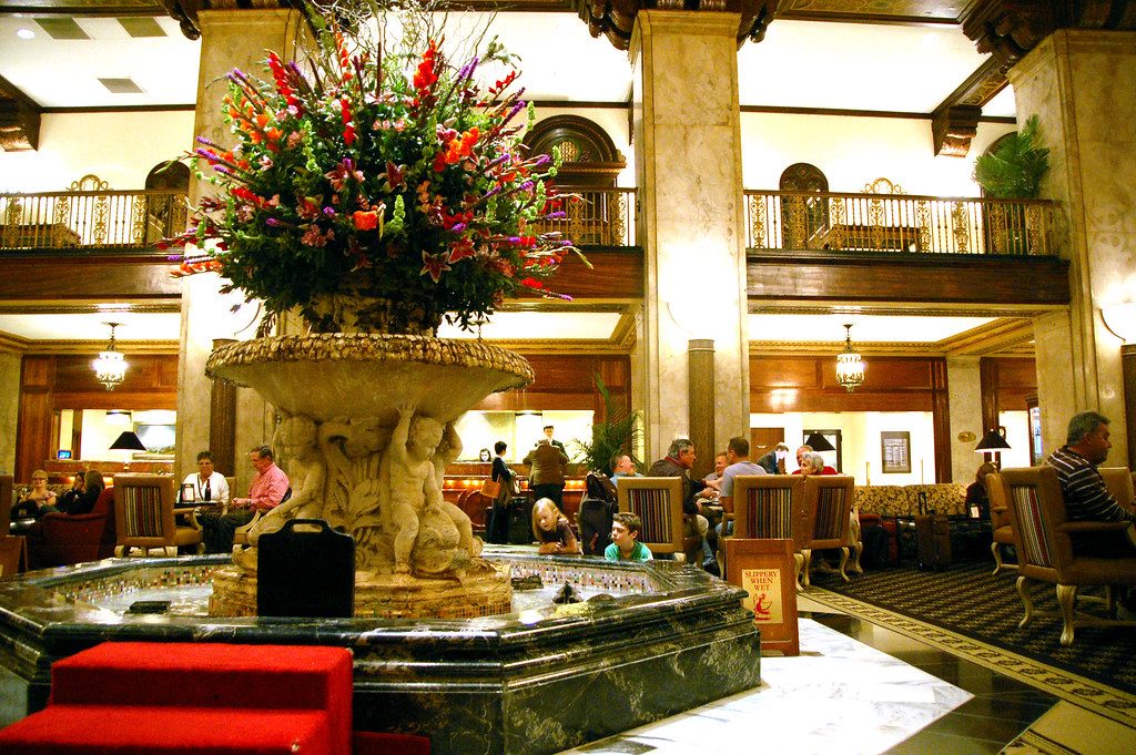 Guests sit in armchairs around the flower-topped marble fountain in the lobby of The Peabody hotel in Memphis
