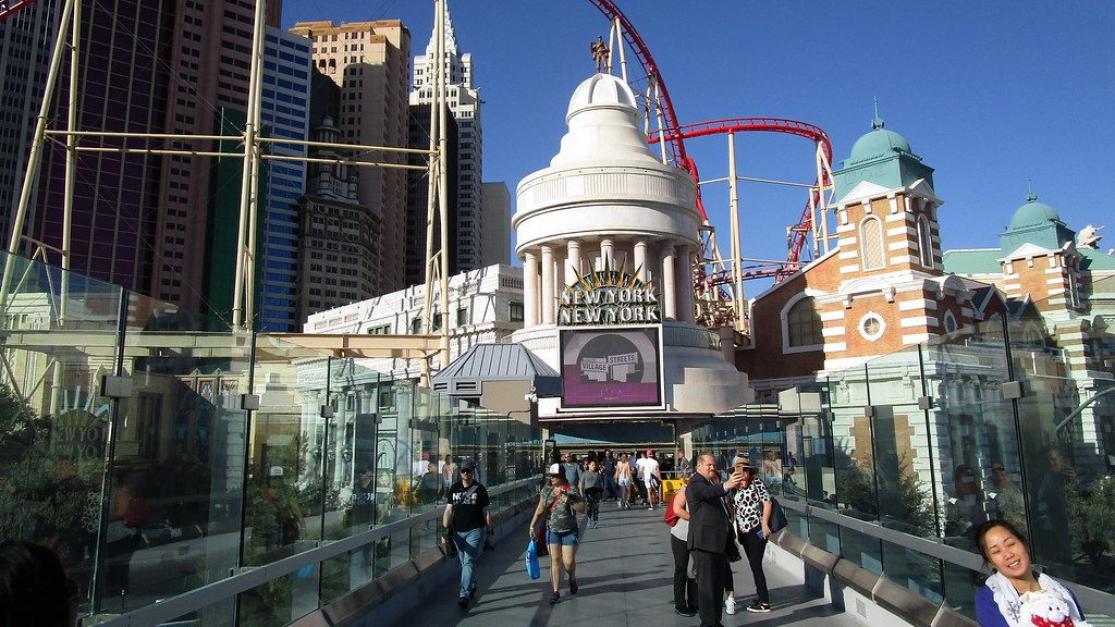 Visitors cross the pedestrian bridge between Excalibur and New York-New York on the Las Vegas Strip in late-day sun