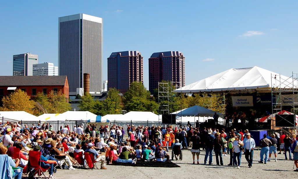 A large festival crowd in front of the National Folk Festival main stage, with Richmond's downtown towers behind