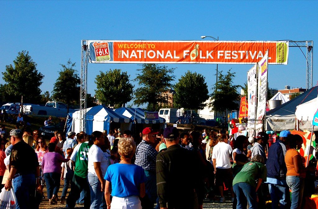 Crowds walking under the orange Welcome to the National Folk Festival banner in downtown Richmond