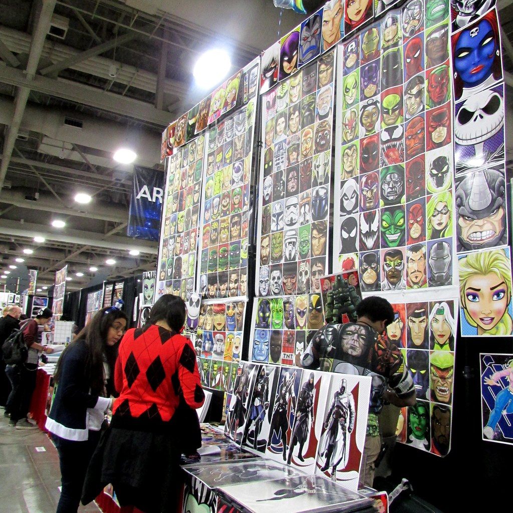 Fans browsing a wall of hand-drawn superhero and villain portrait prints at an artist booth during FanX Salt Lake 2015