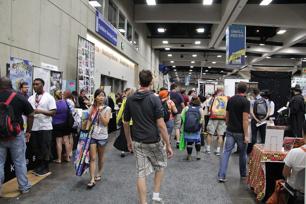 Badge-wearing attendees walking a busy aisle past exhibitor tables in the Small Press area of the San Diego Convention Center during Comic-Con