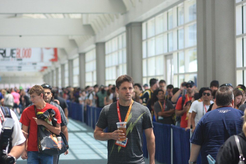 Badge-wearing attendees lining up along a glass concourse inside the San Diego Convention Center during Comic-Con