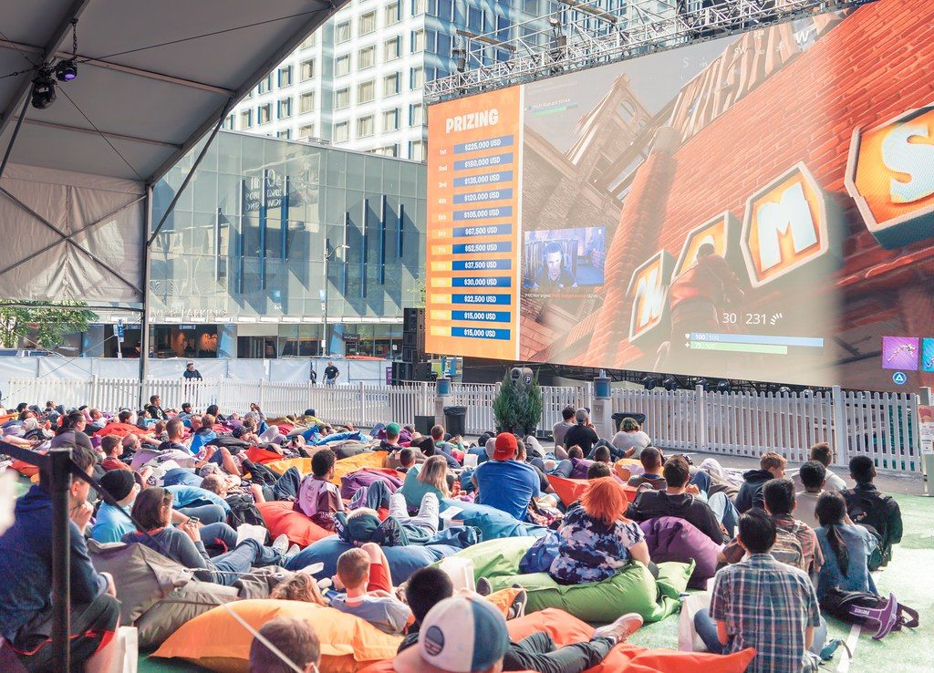 A crowd of gamers lounging on beanbags in front of a giant outdoor screen at PAX West 2018 in downtown Seattle