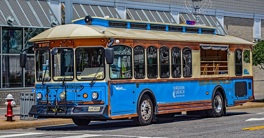 A blue and wood-trimmed Virginia Beach Wave trolley bus at a stop on Atlantic Avenue