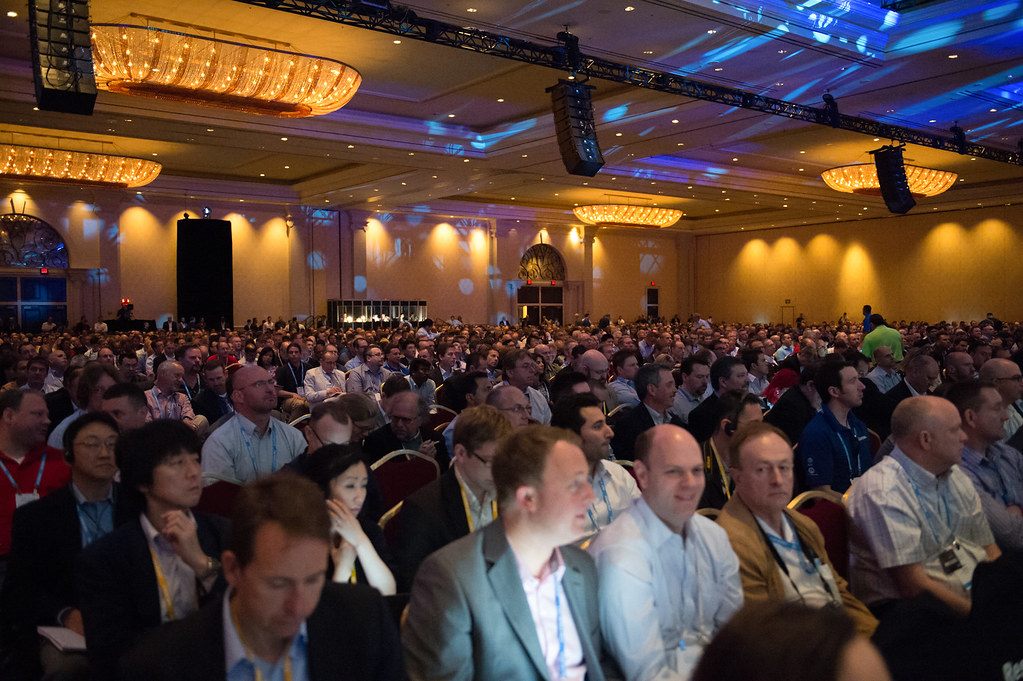 Rows of badge-wearing attendees seated in a chandeliered ballroom at the Venetian during EMC World 2013