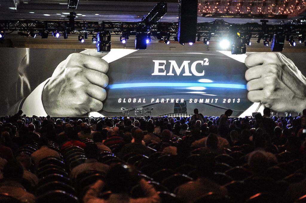 A full house watching a giant EMC Global Partner Summit 2013 screen under stage lighting rigs at the Venetian during EMC World 2013