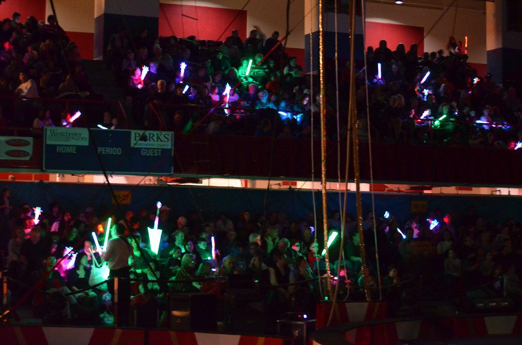 A packed audience waves glowing light-up wands in the darkened stands around the ring at the Royal Hanneford Circus in Westchester, NY