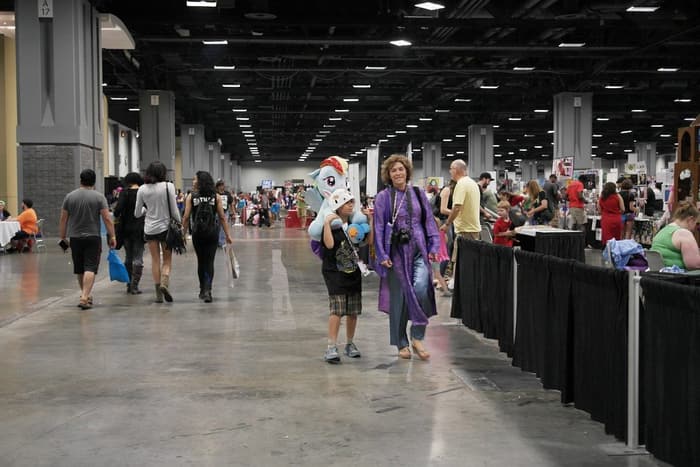 Fans walk a wide aisle past pipe-and-drape booths on the exhibit floor at Awesome Con DC 2015