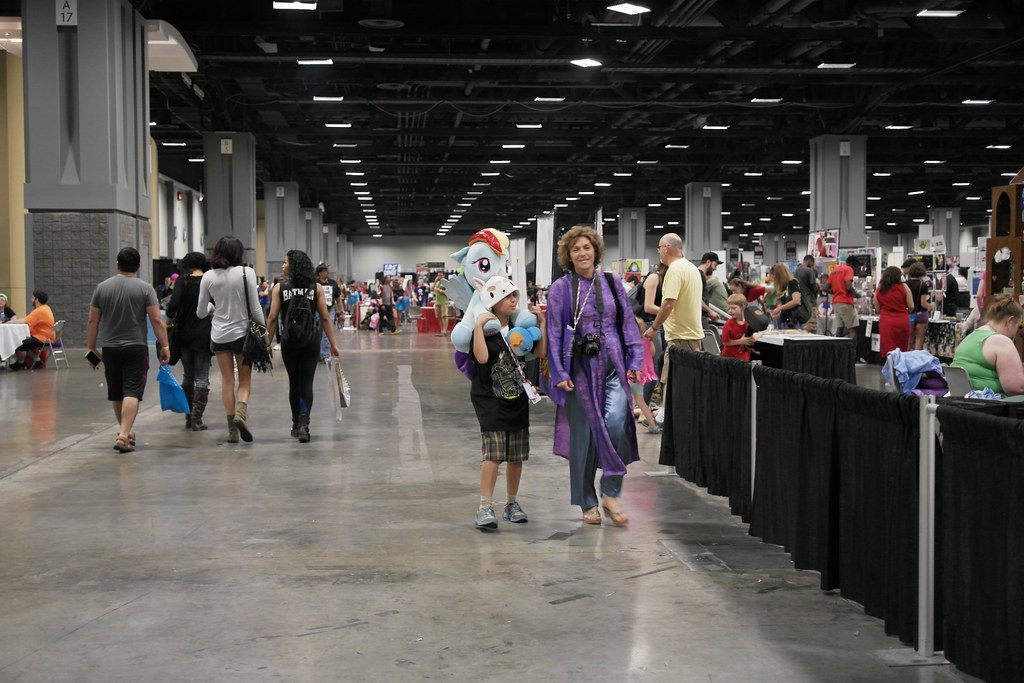 Fans walk a wide aisle past pipe-and-drape booths on the exhibit floor at Awesome Con DC 2015