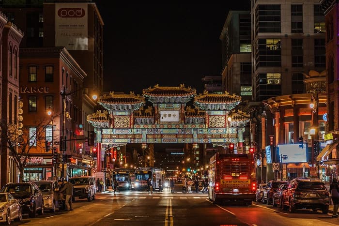 The lit Friendship Archway over H Street in Chinatown at night, with buses, restaurants and pedestrians