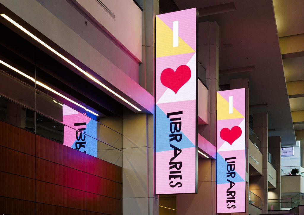 Tall I Love Libraries banners lit in pink, yellow and blue along a convention center concourse during the National Book Festival