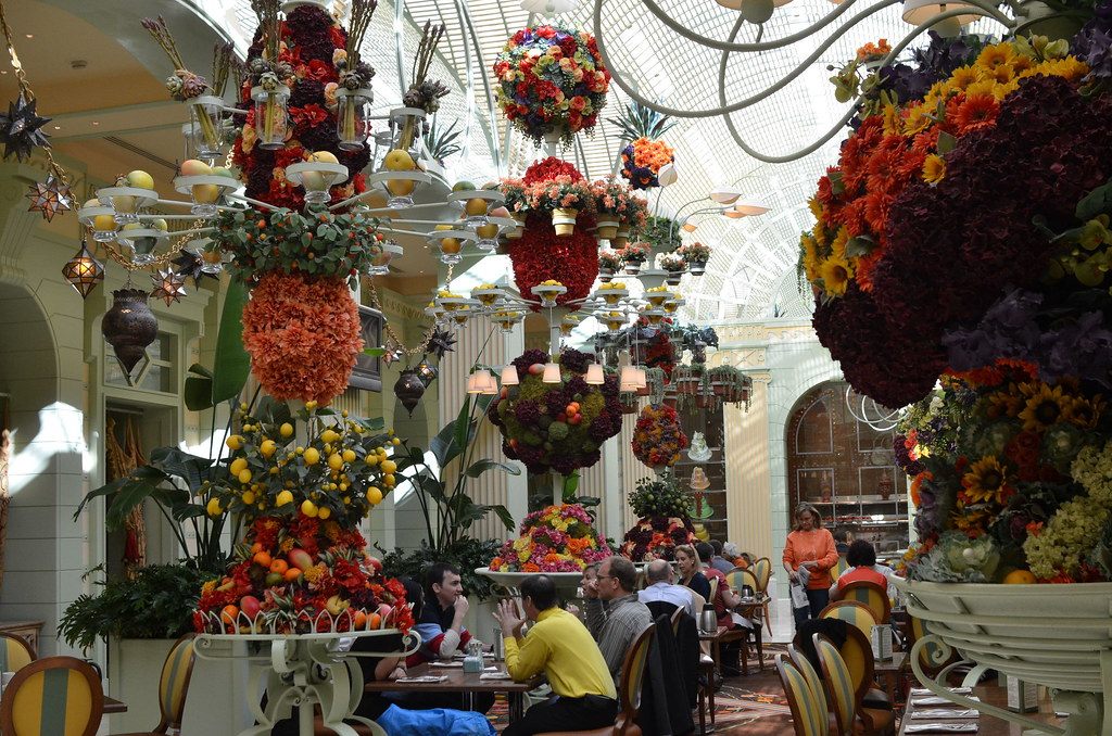 Diners at The Buffet at Wynn under towering floral and fruit displays and a skylit ceiling