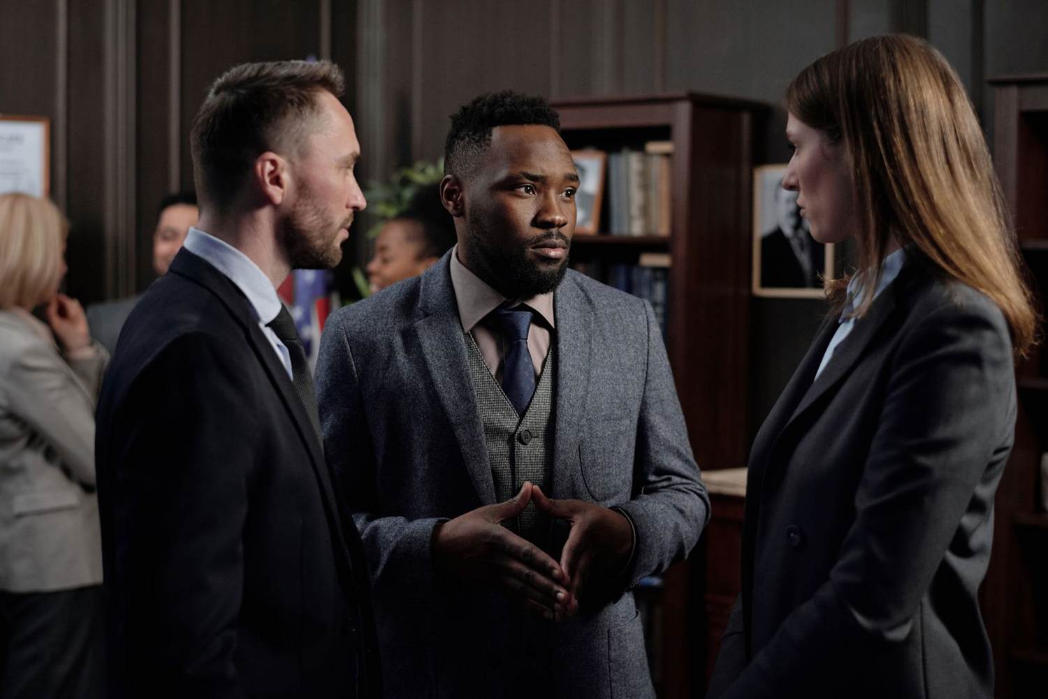 Three people in suits talking at a reception