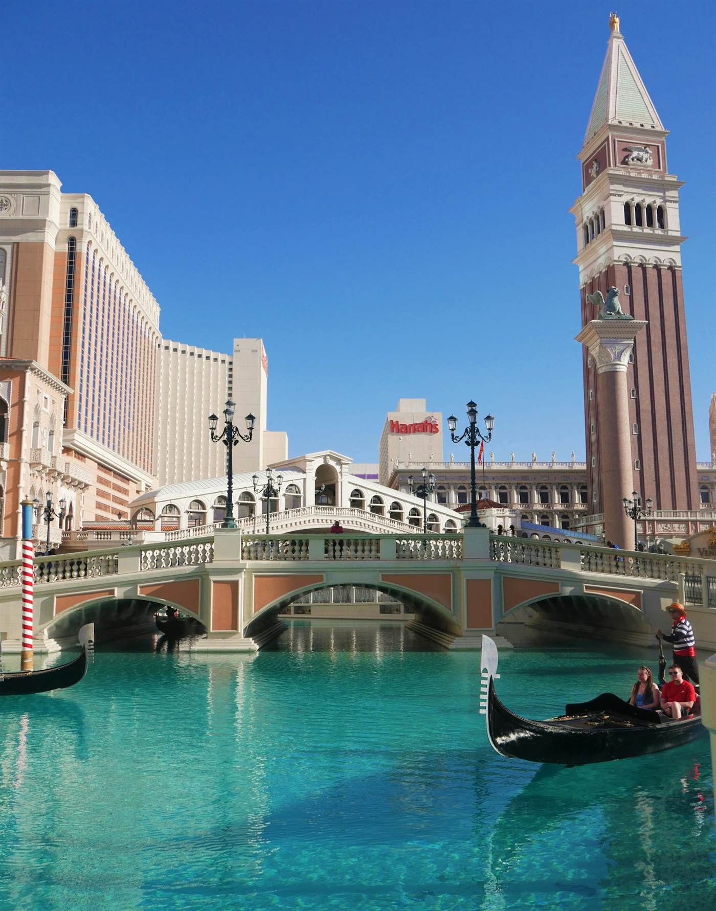 A gondola passing under the Rialto bridge on the Venetian's canal with the campanile behind