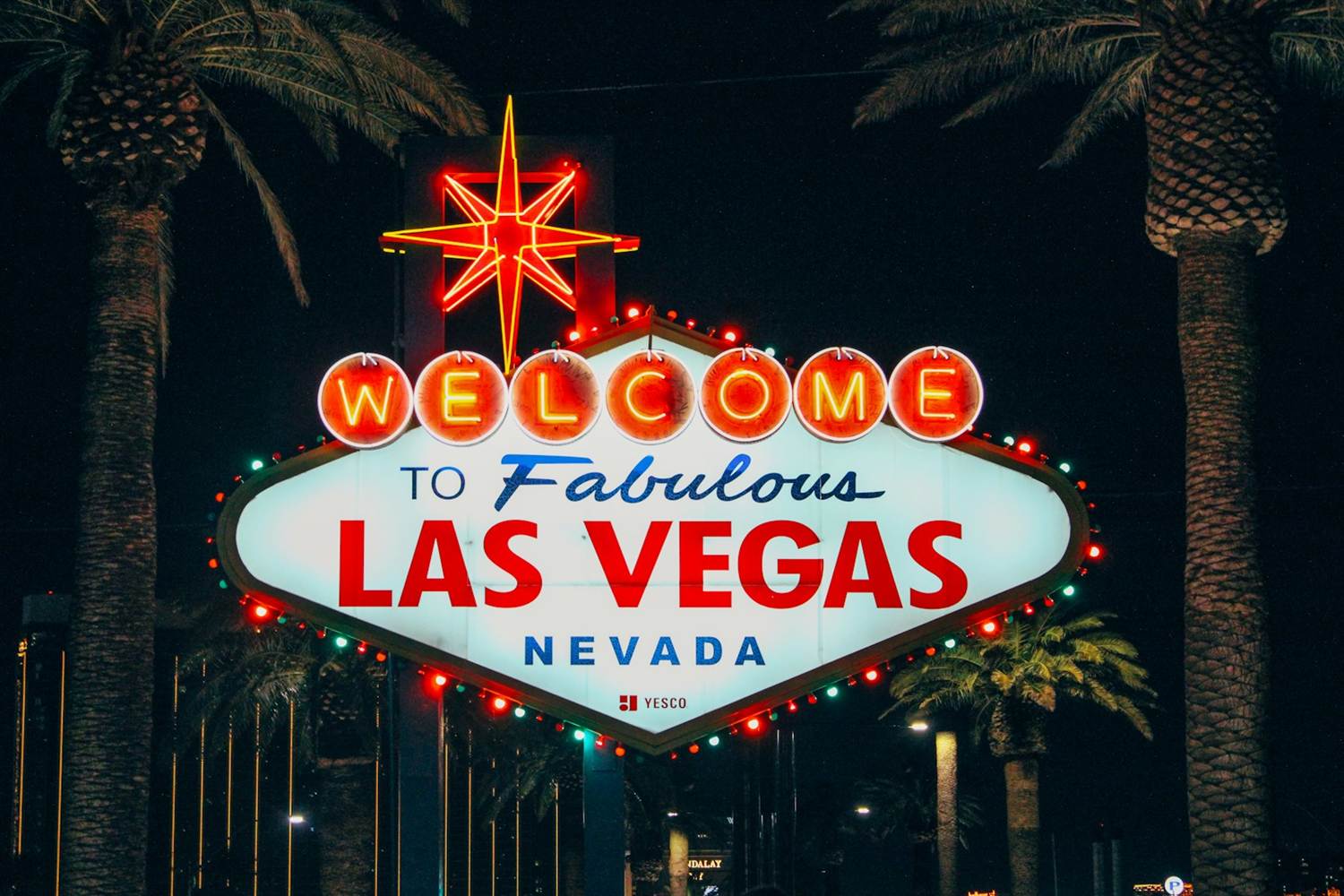 Welcome to Fabulous Las Vegas sign lit at night between palm trees