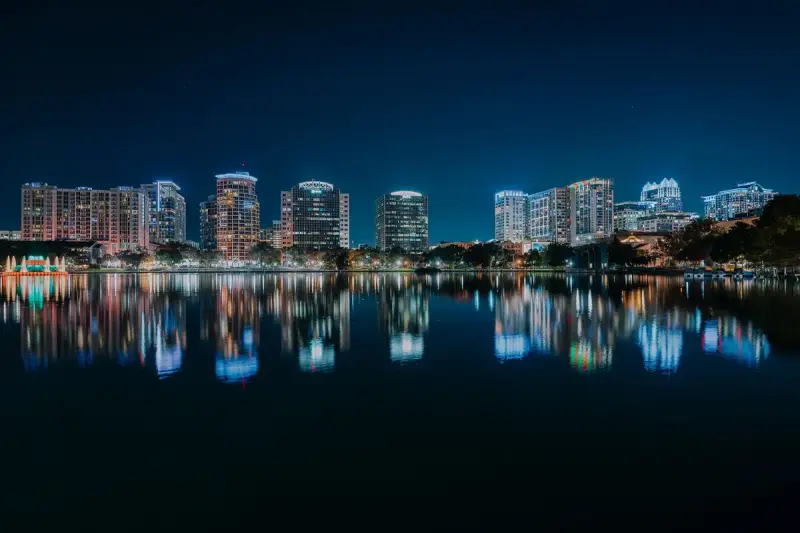 Downtown Orlando towers lit at night and reflected in a calm lake