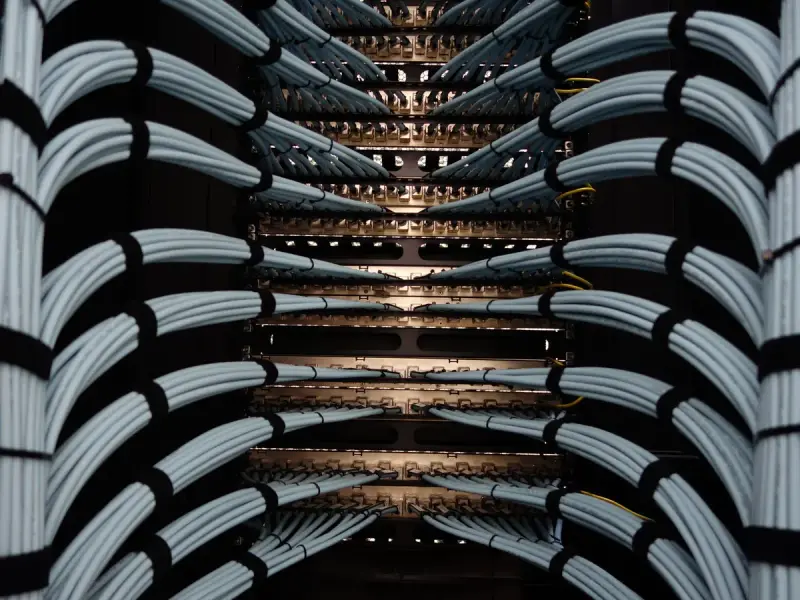 Symmetrical bundles of grey network cables routed into a rack in a dark server room