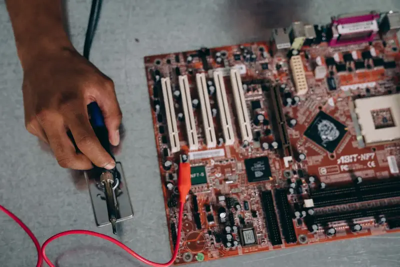 An engineer uses a soldering tool on a circuit board in a workshop
