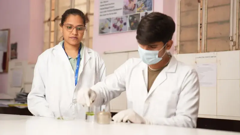 Two young scientists in lab coats carry out an experiment together