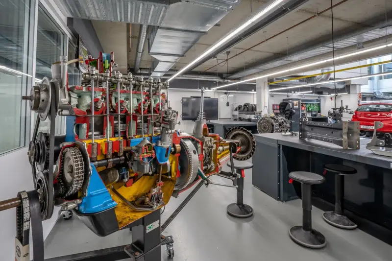 A bright automotive engineering workshop with a cutaway drivetrain and test benches