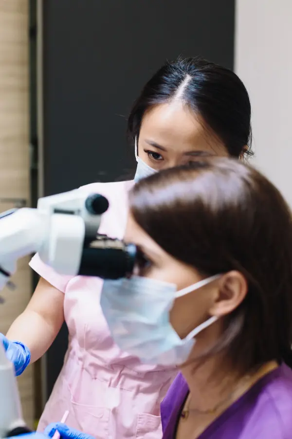 Two dental professionals working at a microscope