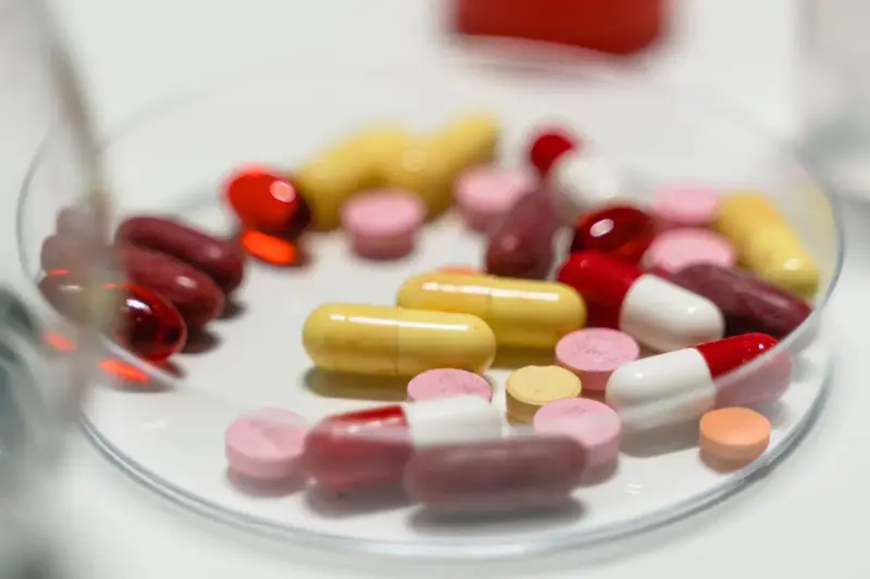 Colorful capsules and tablets arranged in a glass petri dish