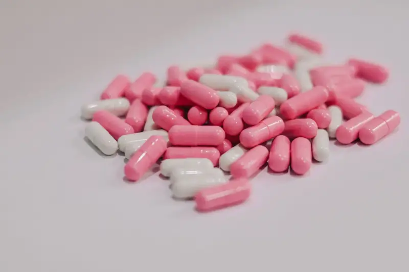 Pile of pink and white two-piece capsules on a white surface
