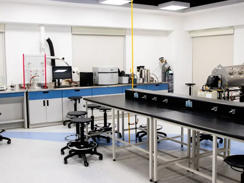 Clean, spacious research lab with black benches, stools, fume hoods and instruments