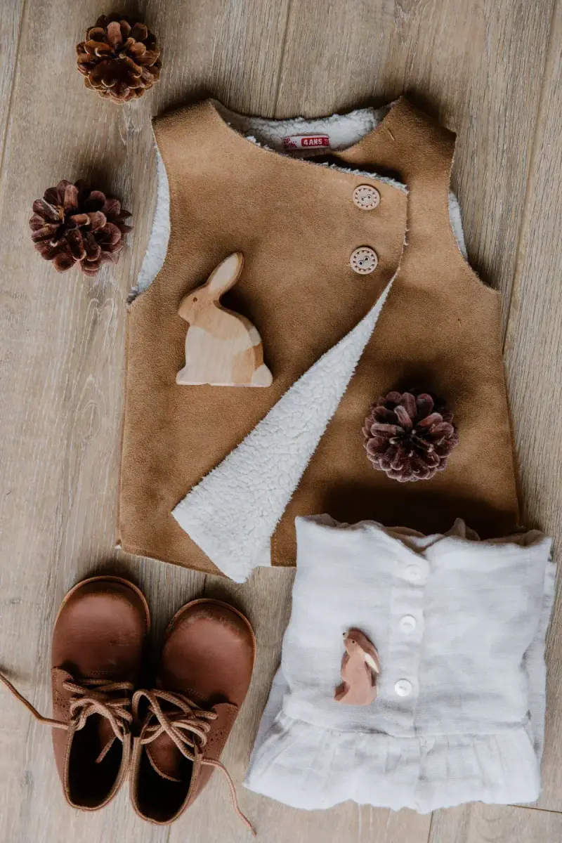 Children's clothing and footwear arranged on a wooden floor