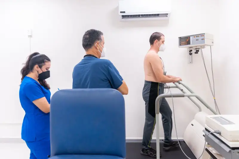 Cardiology team in scrubs watching a patient walk a treadmill during a cardiac stress test