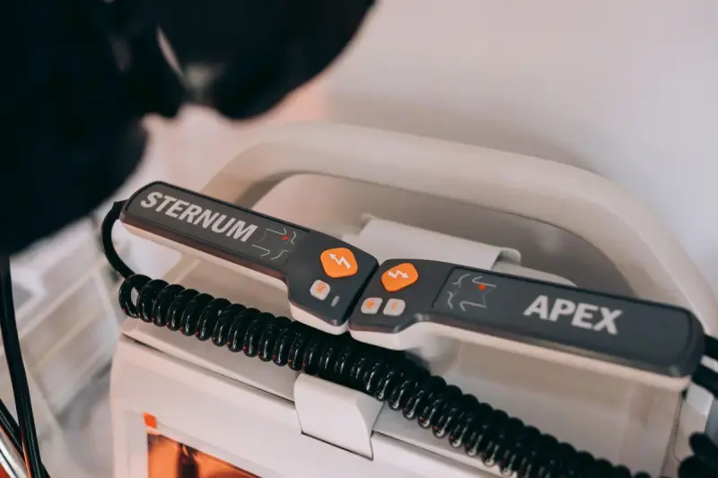 Defibrillator paddles labeled sternum and apex resting in their holder on the unit
