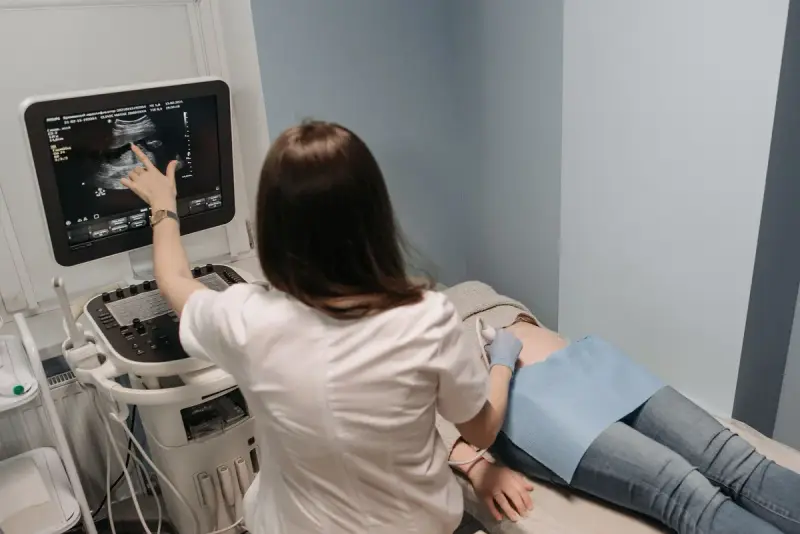 Female physician scanning with an ultrasound probe and pointing to the image on the screen