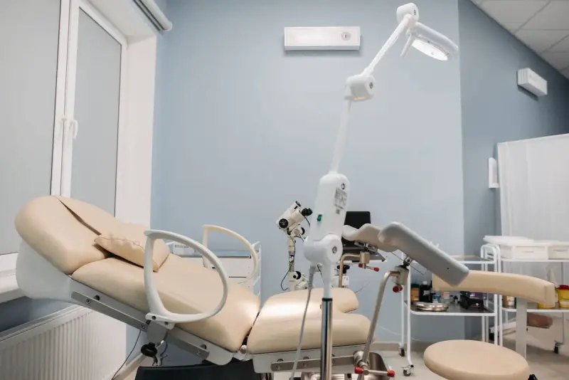 Gynecology examination chair with a colposcope and exam light in a bright clinic room
