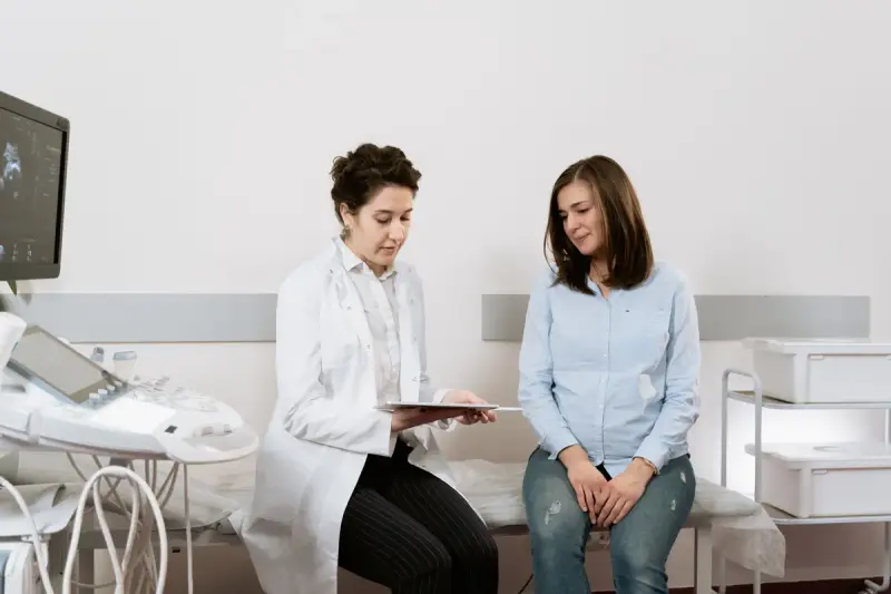Doctor in a white coat reviewing results on a tablet with a patient beside an ultrasound unit