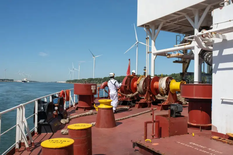 Crew member handling equipment on a vessel with offshore wind turbines behind