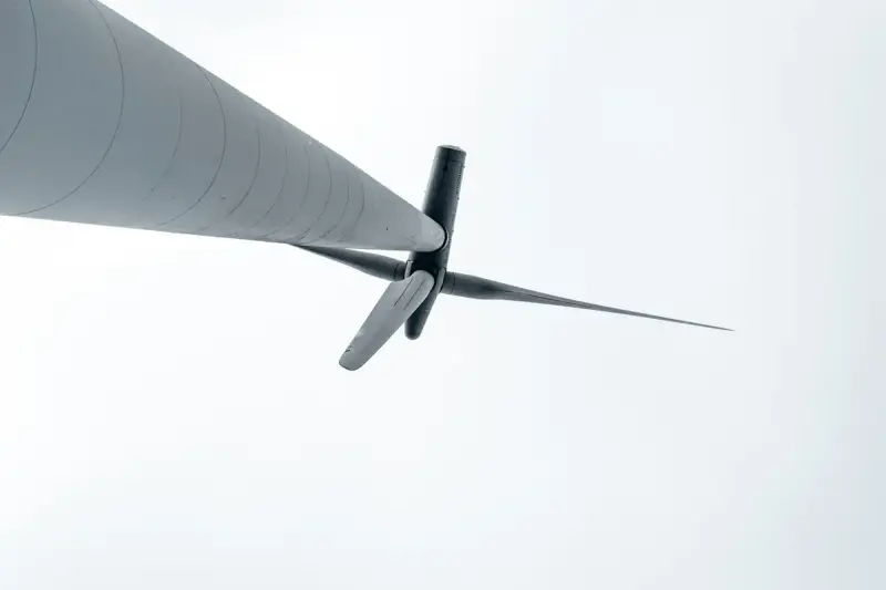 Low-angle view up the tower of a wind turbine to its hub and blades