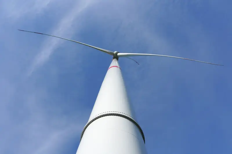 Close view of a wind turbine nacelle and rotor against a clear sky