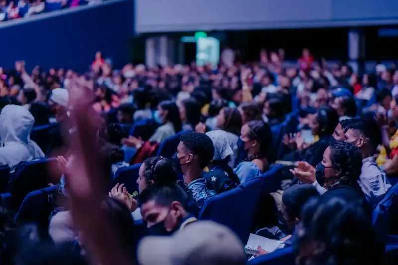 Large audience seated in rows watching a live indoor event