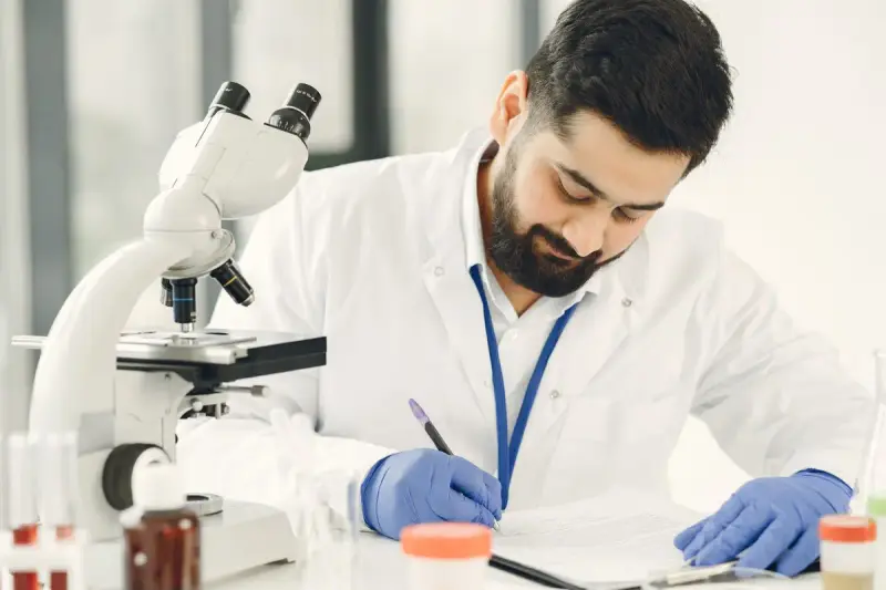 Male scientist in a laboratory taking notes beside his samples