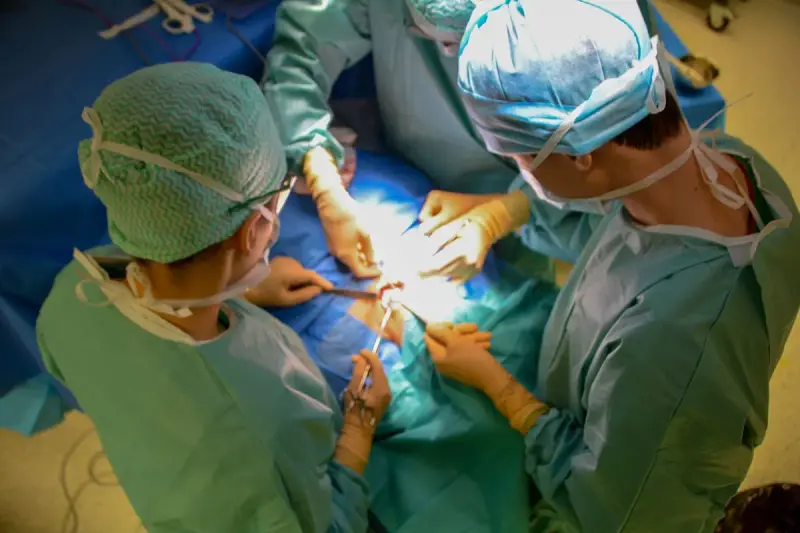 Overhead view of two surgeons in caps and gowns working with clamps over sterile drapes