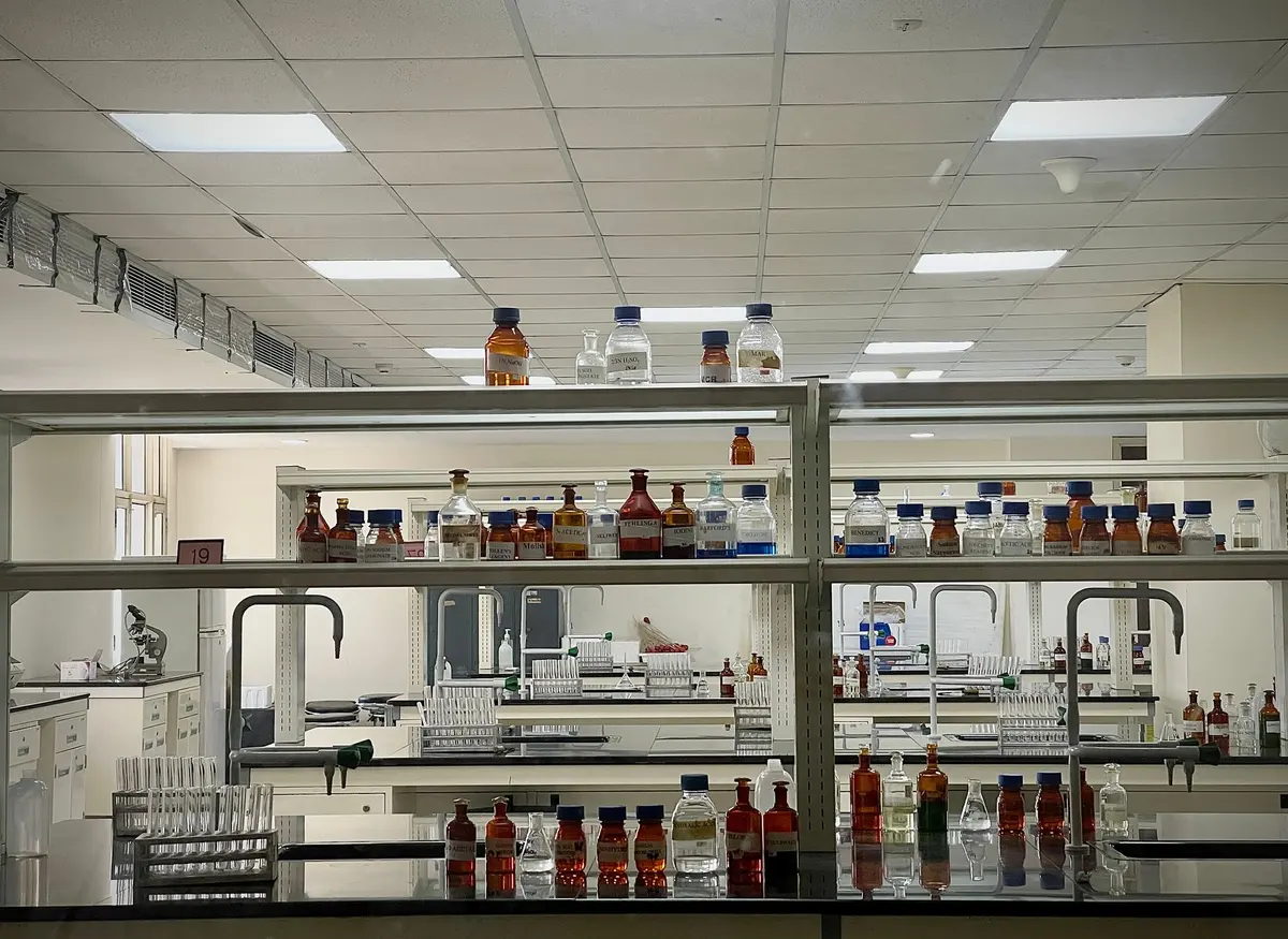 Chemistry laboratory with reagent bottles on shelves above long lab benches