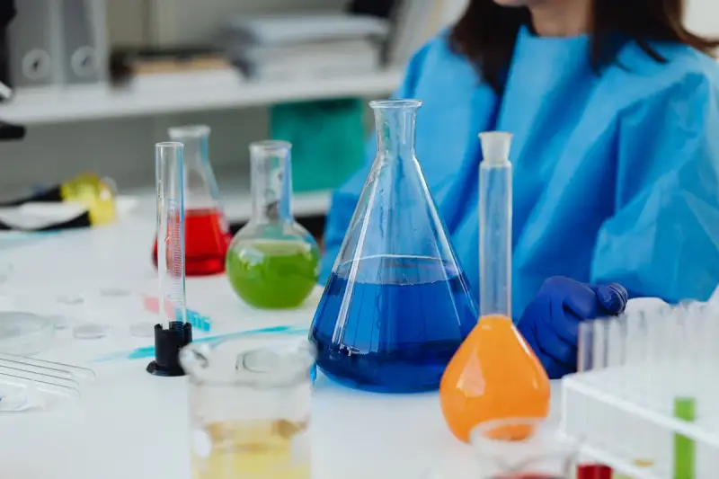 Erlenmeyer flasks and graduated cylinders holding blue, green, red and orange liquids